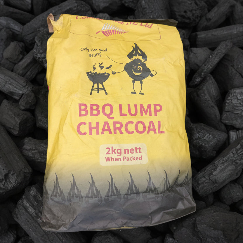 Bag of BBQ lump charcoal with a yellow label on a bed of charcoal.